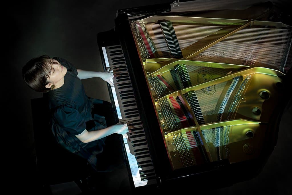 Overhead view of a Kawai grand piano's gold soundboard and strings