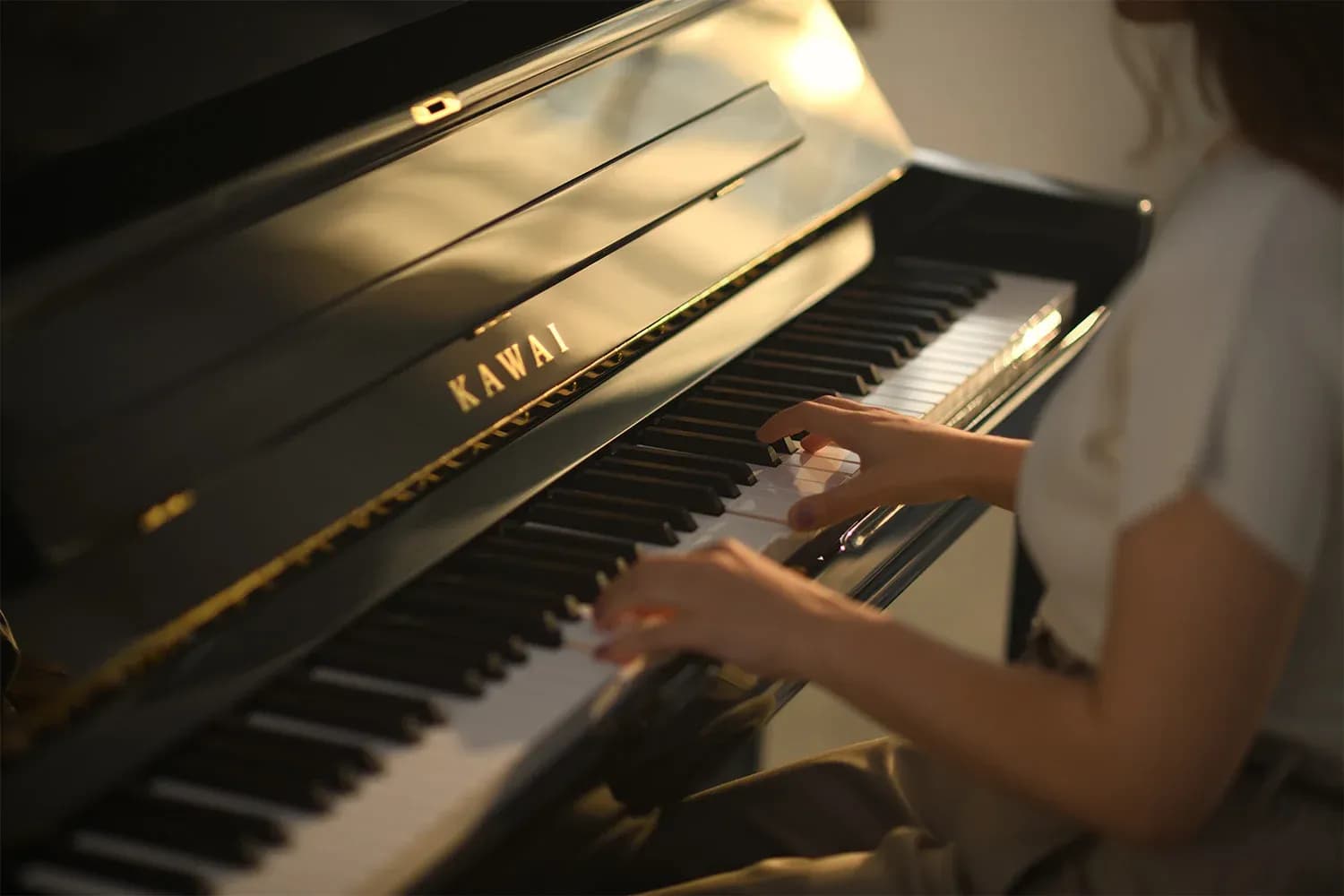 A pianist performing on a Kawai piano in warm light