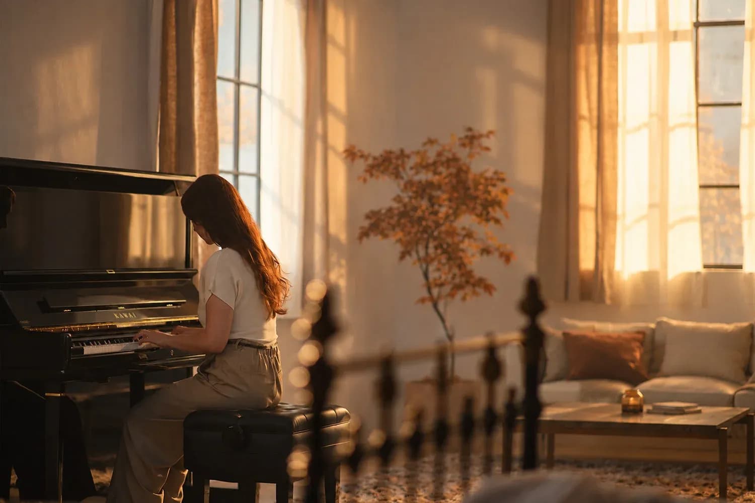 A pianist playing a Kawai upright piano in a sunlit autumn room